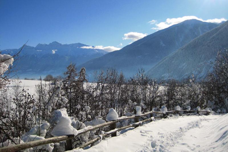 Snow-covered path beside a wooden fence in the mountains